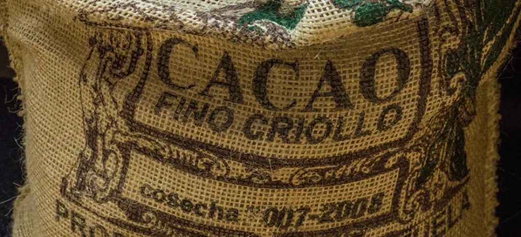 Tacos de pollo “mole-style” con cacao y chile ancho 1 saco de yute con la inscripción “CACAO fino criollo”, textura de fibra en primer plano