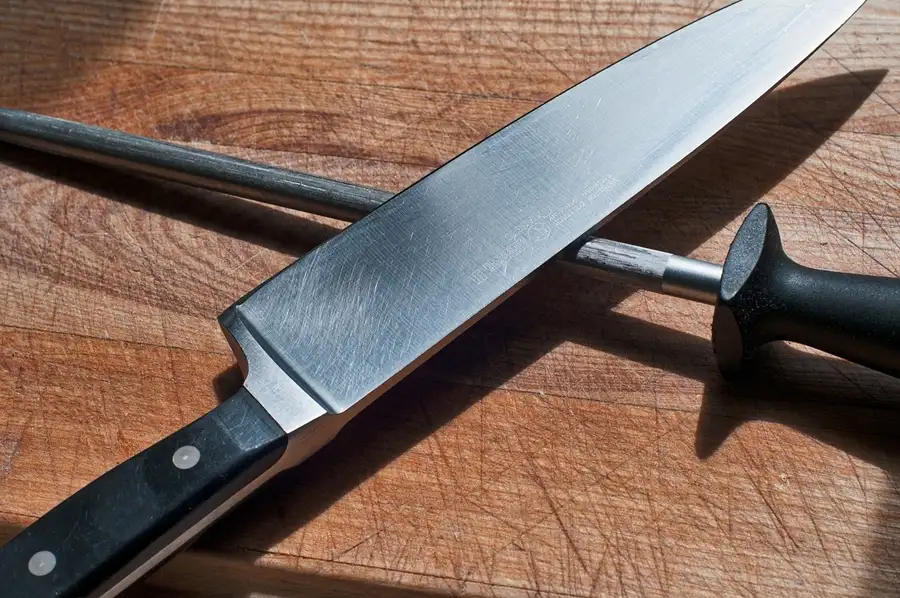 cuchillo de cocina con un afilador de cuchillos en un fondo de madera